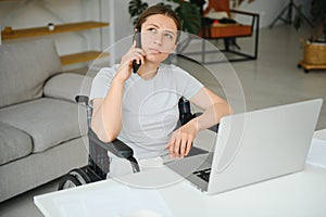 woman in a wheelchair works on the laptop PC in the home office with an assistance dog as a companion