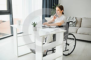 woman in a wheelchair works on the laptop PC in the home office with an assistance dog as a companion