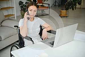 woman in a wheelchair works on the laptop PC in the home office with an assistance dog as a companion
