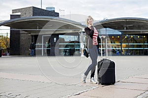 Woman With Wheeled Luggage Standing Outside Railroad Station