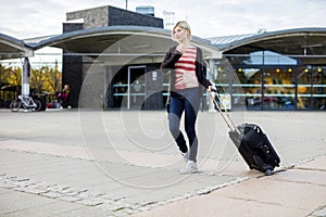 Woman With Wheeled Luggage Walking Outside Train Station