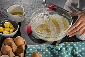 Woman whisking batter of beaten eggs and milk in a bowl
