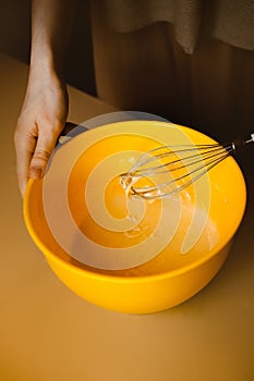 A woman whisking dough in a mixing bowl at home in her kitchen, preparing a homemade bakery delight for breakfast