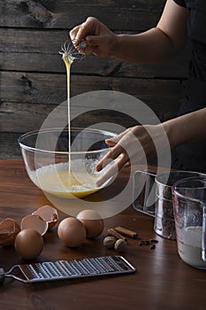 A woman whisking eggs and spices in a bowl at kitchen