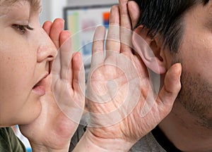 Woman is whispering gossip to man who holds his hand near ear and listening