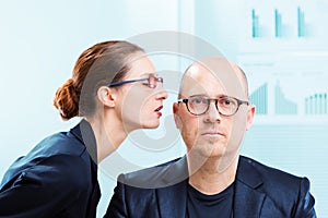 Woman whispering into man ear at office
