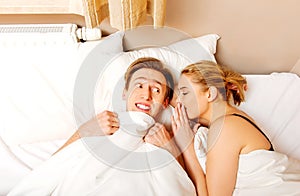 Una donna sussurrando sul suo marito un lui ridere 