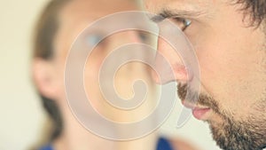 Woman whispers in the man`s ear secret. He`s surprised and smiling. Profile of a man close-up. Woman`s face is blurry