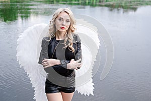 woman with white angel wings. wearing black leather clothes. fallen dark angel. demon. beast. girl in angel costume on