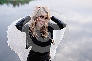 woman with white angel wings. wearing black leather clothes. fallen dark angel. demon. beast. girl in angel costume on