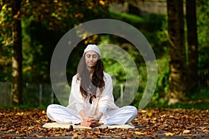 Woman in white in autumn park while doing yoga photo