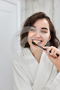 woman in white bathrobes brushing teeth in front of mirror