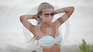 woman in white bikini posing for the photographer on the beach