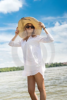 woman in white blouse and straw hat resting on a hot summer day walking on lake