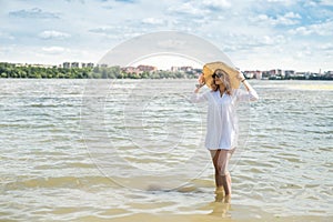 woman in white blouse and straw hat resting on a hot summer day walking on lake