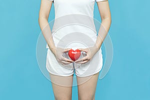 Woman in white clothes holding red heart put on the genitalia area, Penis pain or Itching urinary Health-care concept on blue