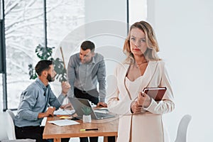 Woman in white clothes standing in front of her employees. Group of business people that working on the project in the office