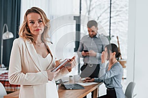 Woman in white clothes standing in front of her employees. Group of business people that working on the project in the office