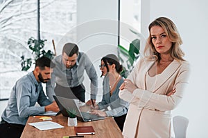 Woman in white clothes standing in front of her employees. Group of business people that working on the project in the office