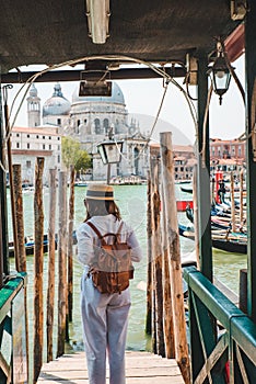 woman in white clothes with straw hat at pier basilica santa maria della salute on background