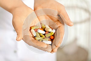 Woman in white coat holding a handful of pills in palms