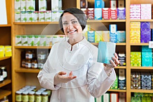 Woman in white coat promoting food additive goods in carton in d