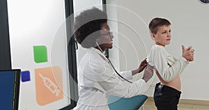 A Woman In A White Coat, Puts A Stethoscope To The Breast Of A Child, Smiles And Listens To A Little Boy Doctor Listens