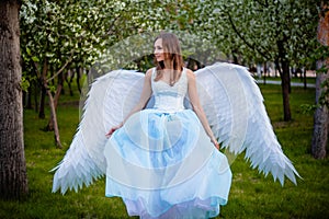 woman in a white corset and blue lush dress with large white angel wings behind her back