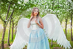 woman in a white corset and a blue puffy dress with large white angel wings behind her back