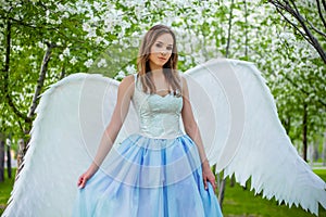 woman in a white corset and a blue puffy dress with large white angel wings behind her back