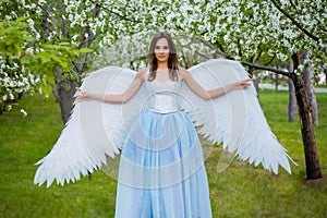 woman in a white corset and a blue puffy dress with large white angel wings behind her back