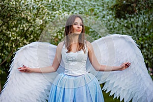 woman in a white corset and a blue puffy dress with large white angel wings behind her back