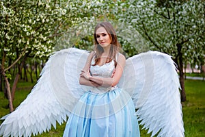 woman in a white corset and a blue puffy dress with large white angel wings behind her back