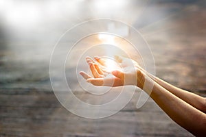 Woman with white cross in hands praying on sunlight photo