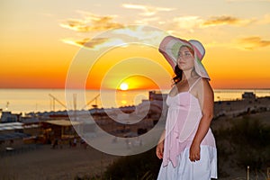 Una mujer en blanco ropa sobre el de el mar sobre el atardecer 