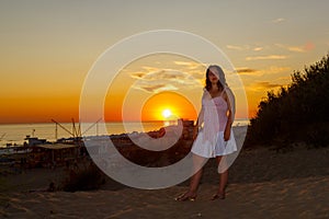 Una mujer en blanco ropa sobre el de el mar sobre el atardecer 