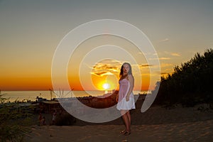 Una mujer en blanco ropa sobre el de el mar sobre el atardecer 