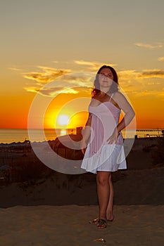 Una mujer en blanco ropa sobre el Playa contra de el mar sobre el atardecer 