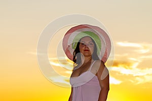 Woman in a white dress and hat on a background of a sunset sky photo