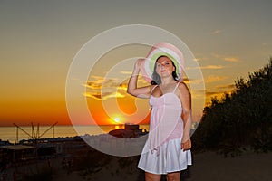 Una mujer en blanco ropa un sombrero sobre el de atardecer el cielo 