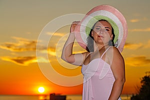 Una mujer en blanco ropa un sombrero sobre el de atardecer el cielo 