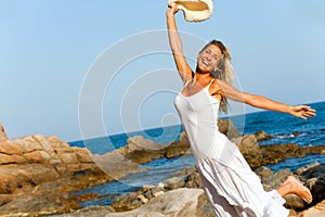 Woman in white dress jumping on beach.