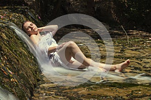Woman with white dress near waterfal stream of water