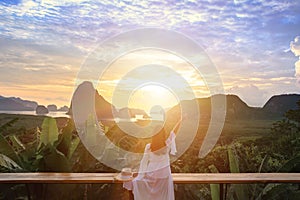 Woman with the white dress sit and see the mountain in early morning  at Samet Nangshe viewpoint in Andaman sea on morning cloudy