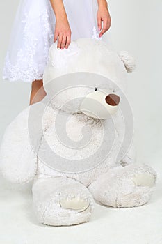 Woman in white dress stands with big toy bear in photo