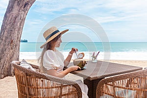 Woman in White Dress and Straw Hat Sitting on Table in Outdoor Beach Cafe