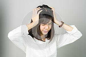 Woman in a white dress is touching head to show her headache. Causes may be caused by stress or migraine.