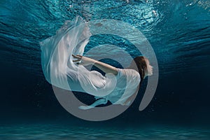 Woman in a white dress under water.