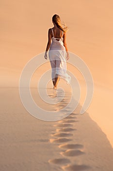 Woman in white dress walking on desert