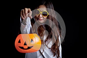 Woman in white ghost spooky costume holds orange pumpkin in dark room, female with makeup scary going to Halloween party.